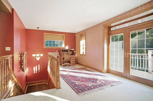 Bright loft landing with home office desk, red walls, and glass balcony doors.