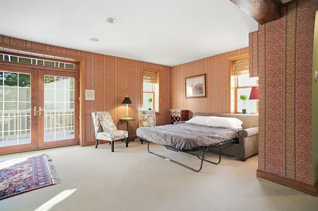 Living area with a pull-out sleeper sofa, patterned wallpaper, and French doors.