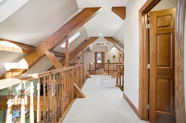Upper hallway loft with exposed wooden beams and skylights.