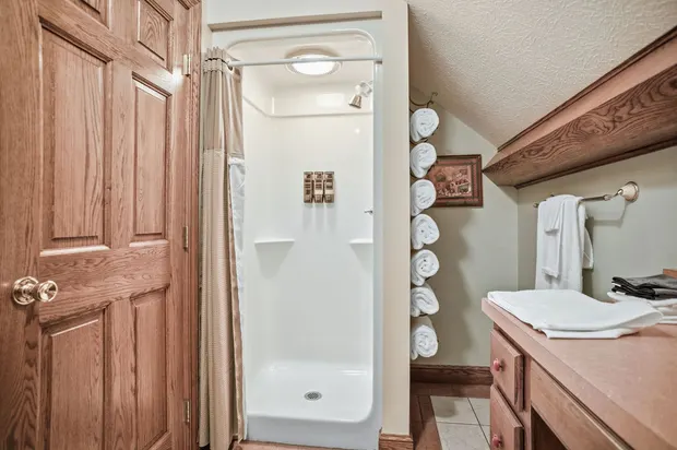 Cozy bathroom walk-in shower with wall dispensers and towel storage.