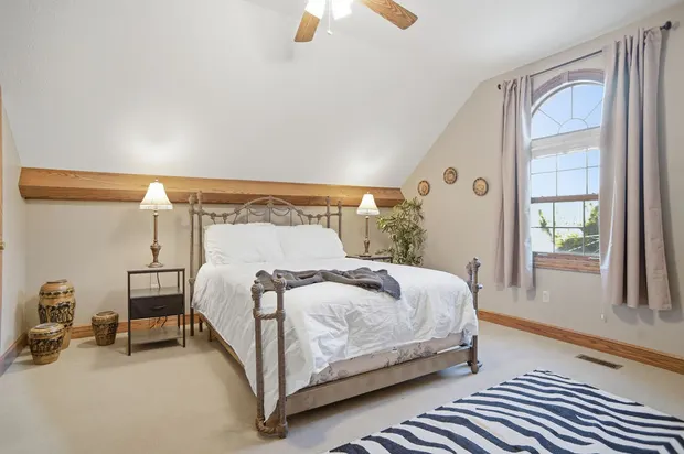 Cozy vaulted ceiling bedroom with a metal bed frame and arched window