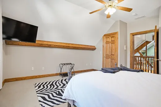 Loft bedroom with wall-mounted TV, slanted ceiling, and zebra rug.