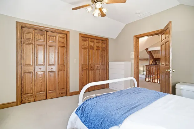 Bedroom featuring dual wooden bifold closets and an open door to a loft hallway.