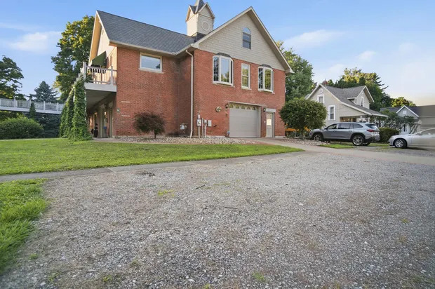 Exterior of a large red brick house with a spacious gravel driveway and garage.
