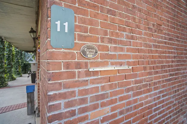 Historic red brick exterior with Century Home 1905 plaque and house number 11.