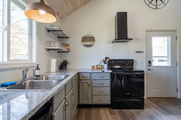 Kitchen with grey cabinets, a black gas stove, and a wood-plank ceiling.