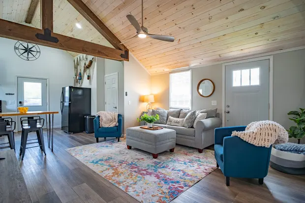 Bright living room with a grey sofa, blue armchairs, and a smart TV.