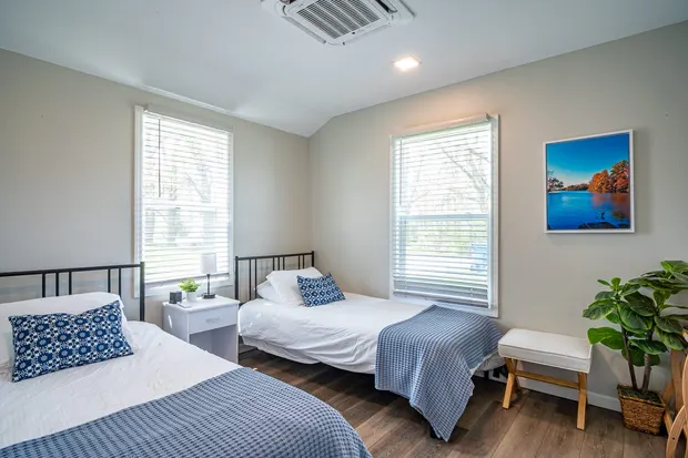 Bedroom with two twin beds, blue-and-white bedding, and windows.