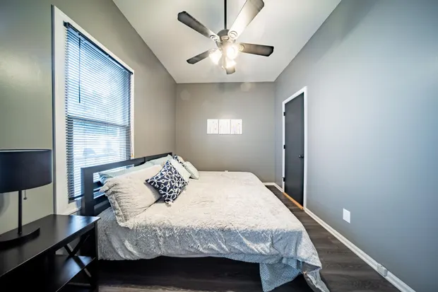 Grey bedroom with a large bed, a small desk, and a window.