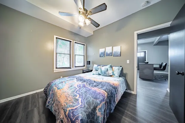 Queen bedroom with blue patterned bedding, open toward the living area.