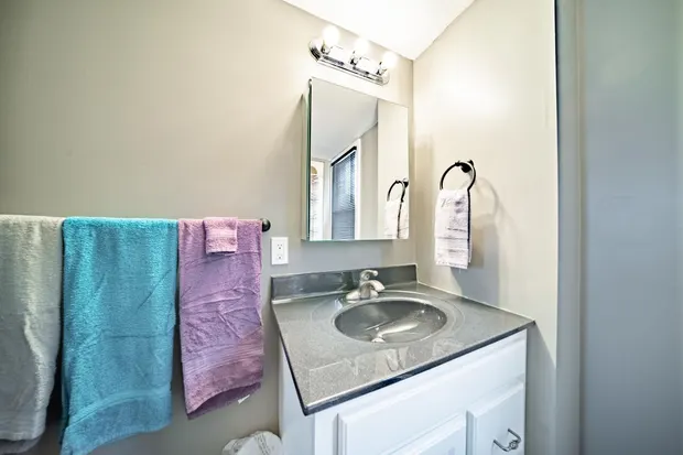 Bathroom vanity with a mirror and colorful hand towels.