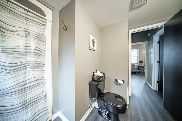 Grey bathroom with a vanity and a view down the hallway.