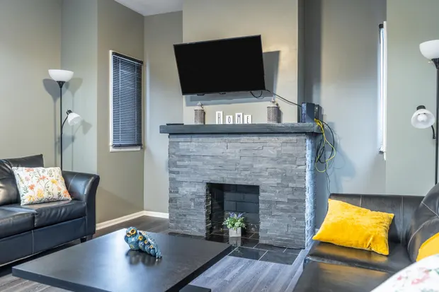 Stone fireplace with a wall-mounted TV above it and a leather sofa alongside.