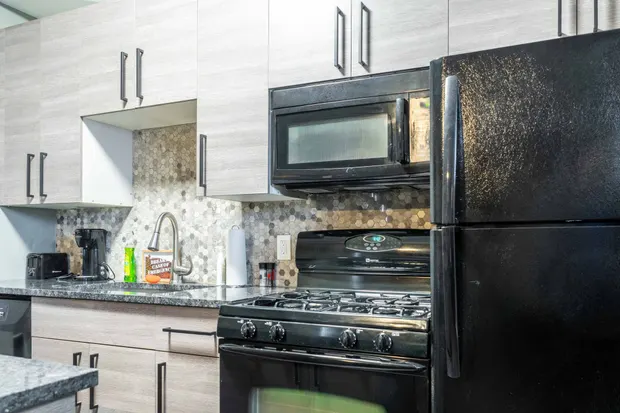 Kitchen with a black gas stove, black refrigerator, and tile backsplash.