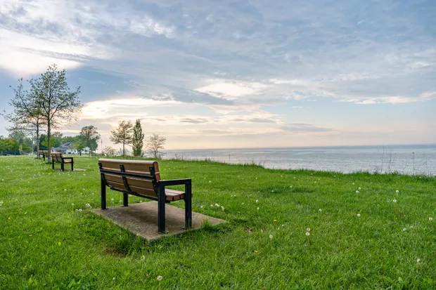 A bench on the grass overlooking Lake Erie at sunset in Showse Park.