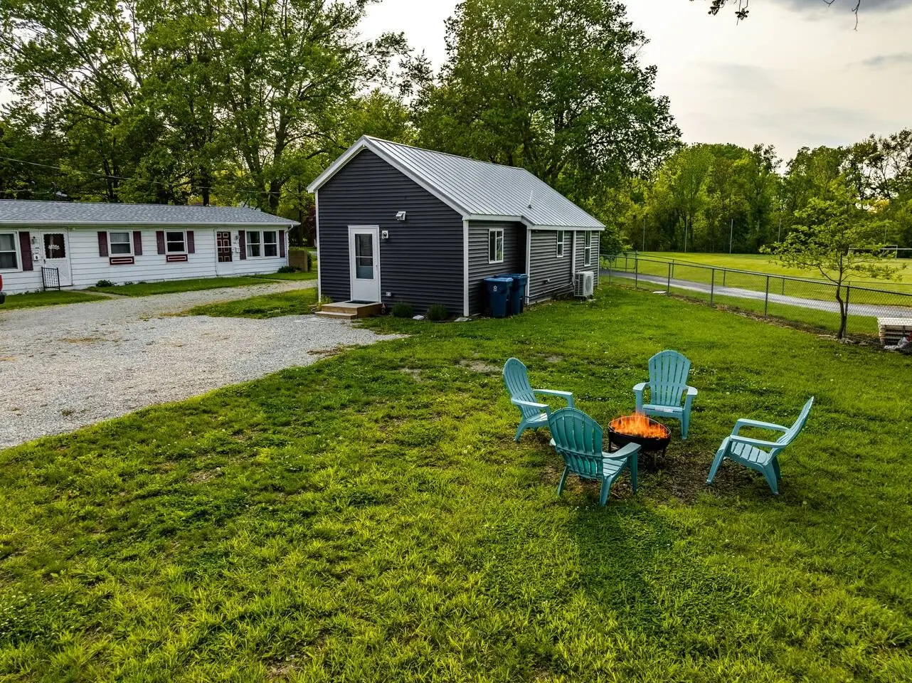 Huron Retreat, vacation rental 20 minutes from Summit Motorsports Park in Huron, Ohio — the backyard fire pit and Adirondack chairs behind the cottage.