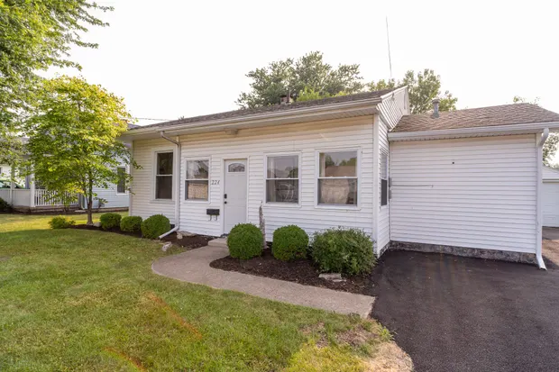 Front of the home with a paved walkway and tidy shrub beds.