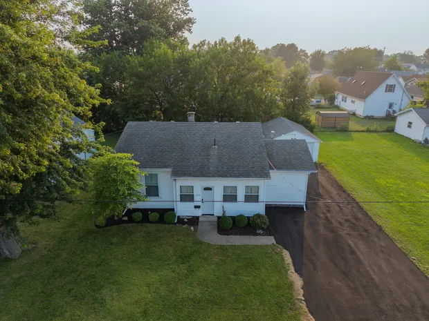 Aerial view of the white single-storey home with a long driveway and green side yard.