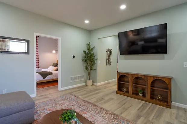 Living room with a wall-mounted Roku TV, sofa, and a view into a bedroom.