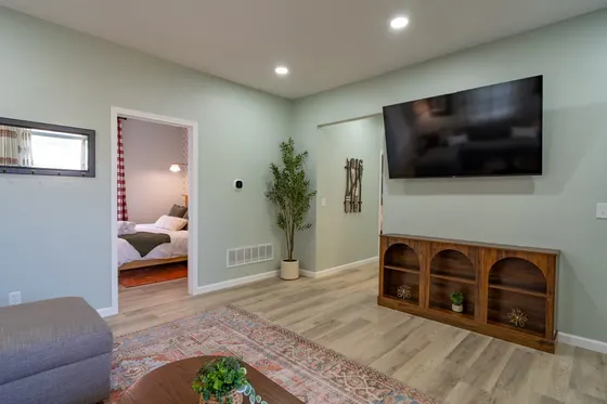 Living room with a wall-mounted Roku TV, sofa, and a view into a bedroom.