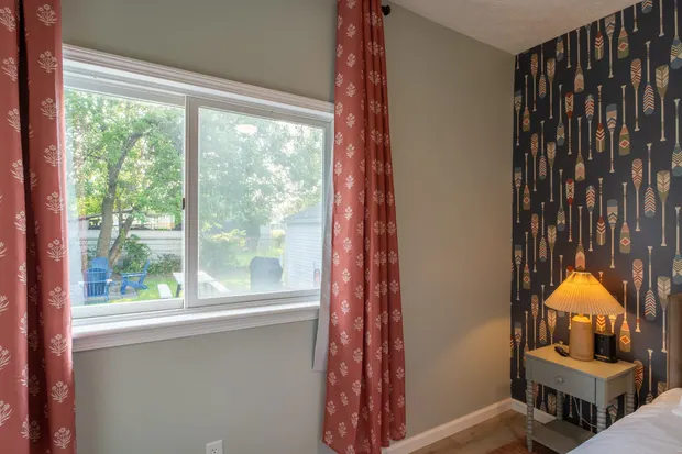 Primary bedroom window with rust curtains and a bedside lamp.