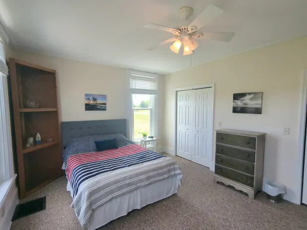 Downstairs queen bedroom with a striped bed and a wardrobe.