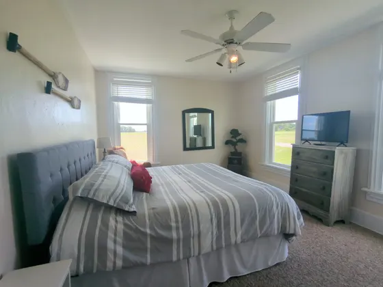 Bedroom with a king bed, upholstered headboard, and a red accent pillow.