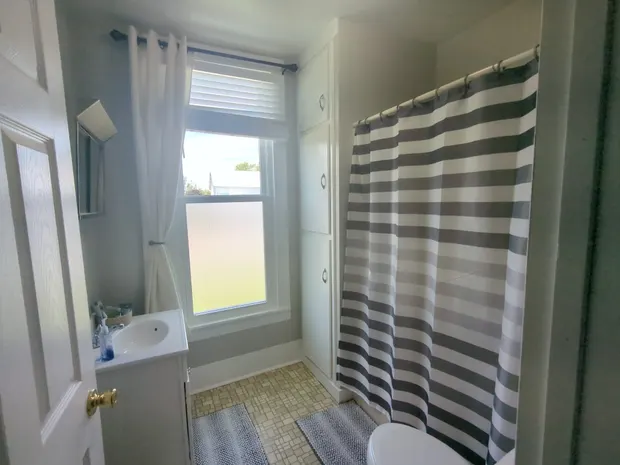 Downstairs bathroom with a striped shower curtain.