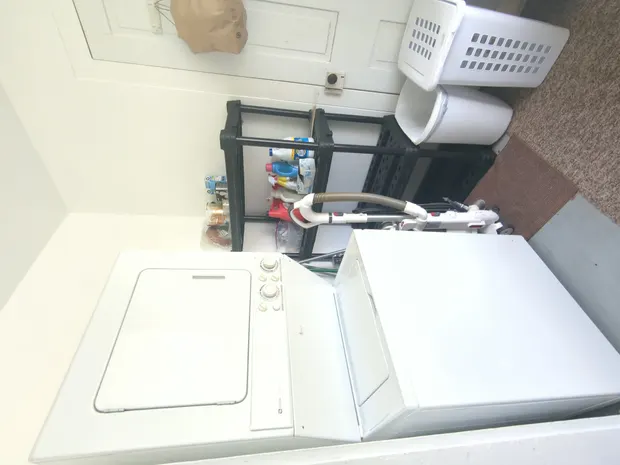 Laundry room with white appliances and black shelving.