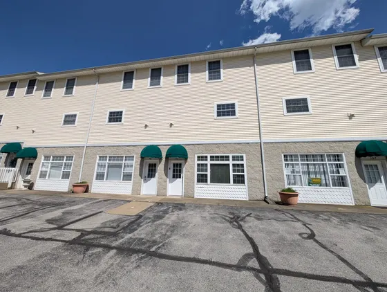 Row of three-story condo units with green awnings under a blue sky.
