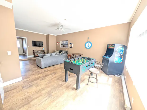 Ground-floor game room with sectional sofas, a foosball table, an arcade game, and a Smart TV.