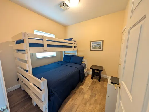 Bunk room with a queen bed and a twin bunk above, in navy bedding.