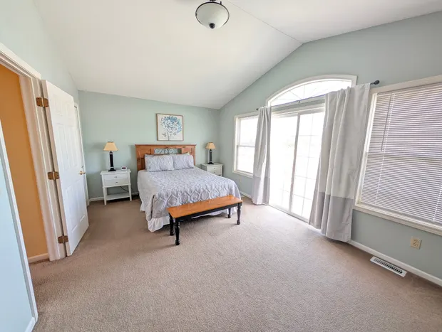Third-floor bedroom with a queen bed, vaulted ceiling, and a sliding door to a balcony.