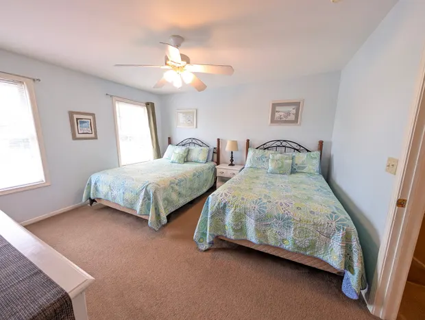 Third-floor bedroom with a queen bed and a full bed in coastal bedding.