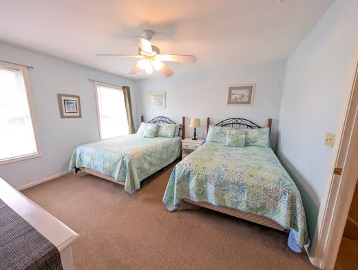 Third-floor bedroom with a queen bed and a full bed in coastal bedding.
