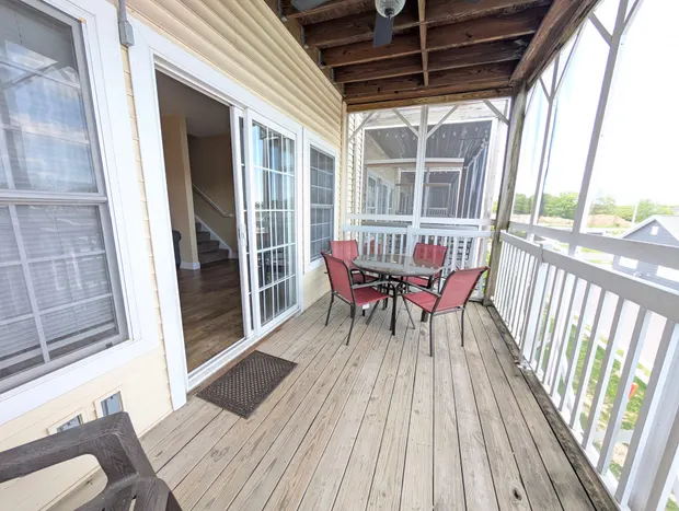 Screened-in balcony with a table and chairs overlooking neighbouring rooftops.