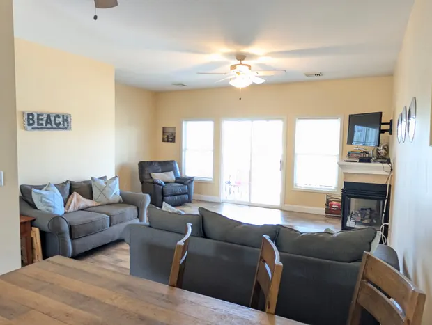 Living room with coastal decor, a "BEACH" sign, and the fireplace.