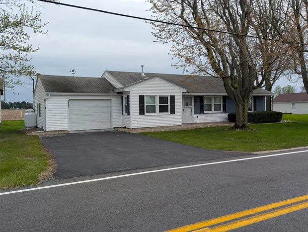 White single-storey house with an attached garage and a large front tree.
