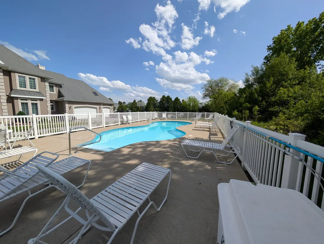 The community pool and sun deck with loungers on a sunny day.