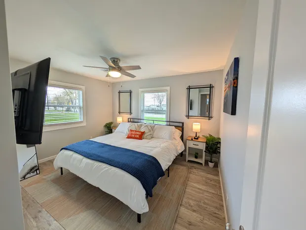 King bedroom with blue and orange accents and a ceiling fan.