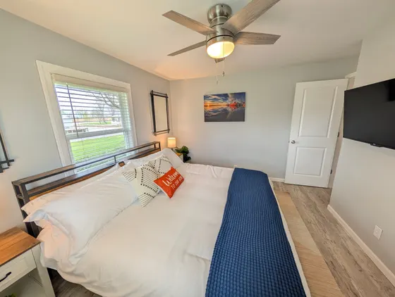 Bedroom with a large king bed, blue throw, and a wall-mounted TV.