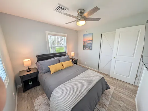 Second king bedroom with grey bedding and yellow pillows.