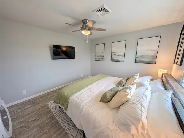 Third bedroom with a full bed, white bedding, and a green throw.