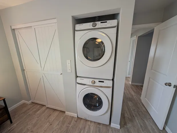 Stacked white washer and dryer in a hallway nook.
