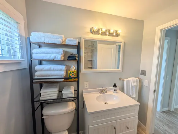 Bathroom vanity, toilet, and towel shelves.