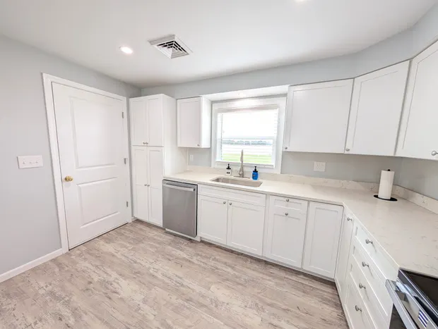 White kitchen with light wood flooring.
