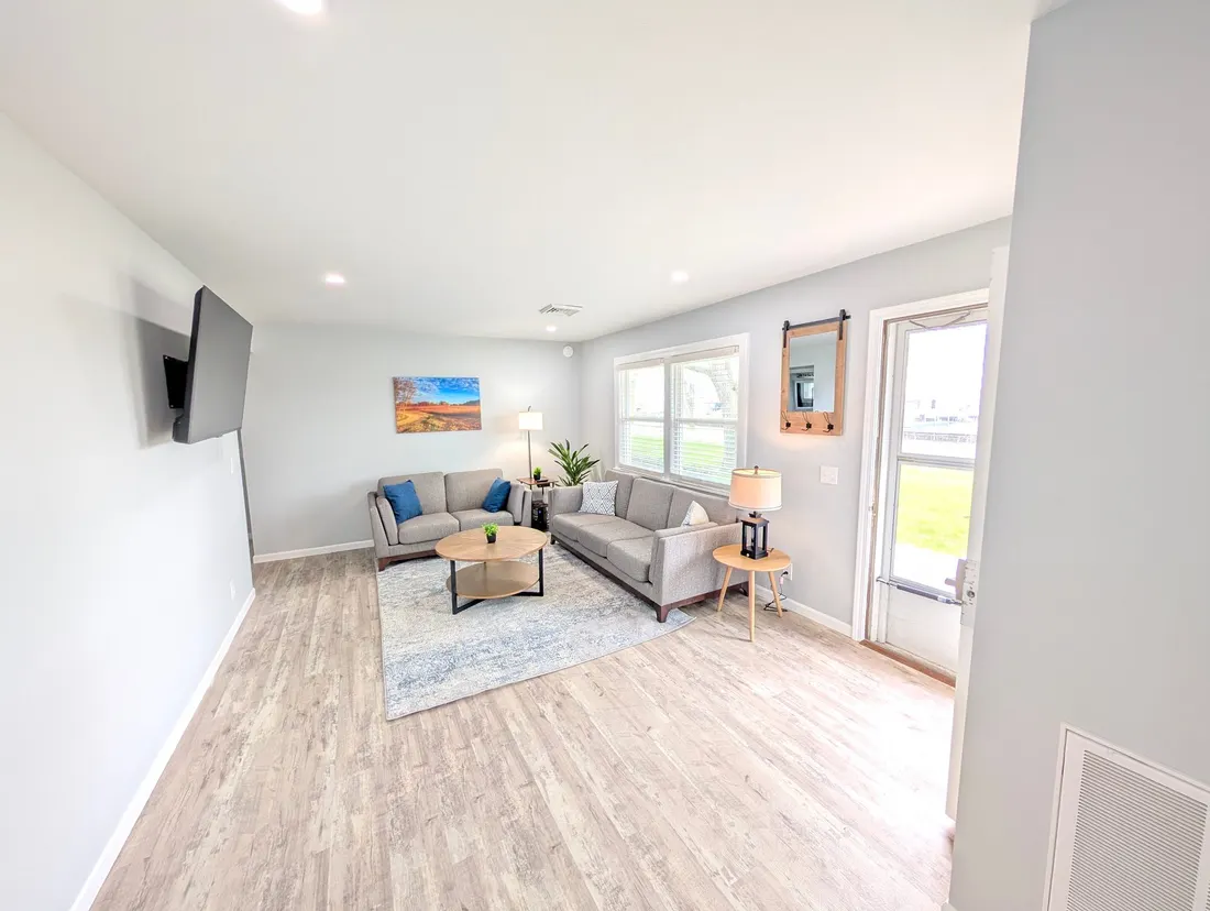 Living room with grey sofas and light wood floors.
