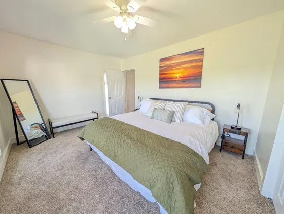 Upstairs king bedroom with a green quilt and sunset wall art.