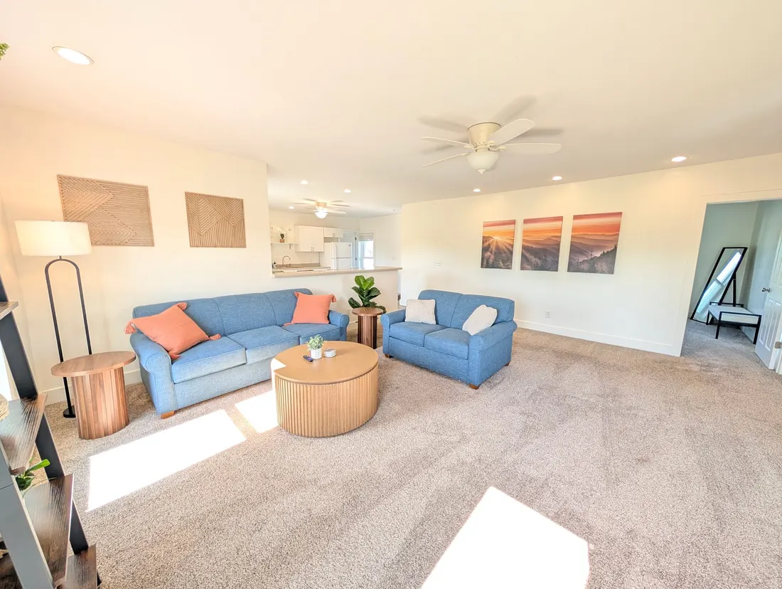Living room with blue sofas and a round wooden coffee table.