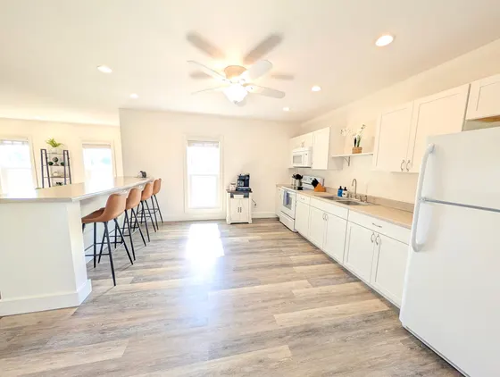 Bright modern white kitchen with a breakfast bar and stools.